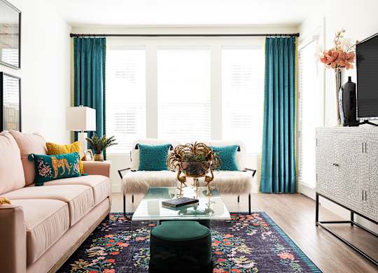 A living room with a pink couch, a coffee table, and a television.