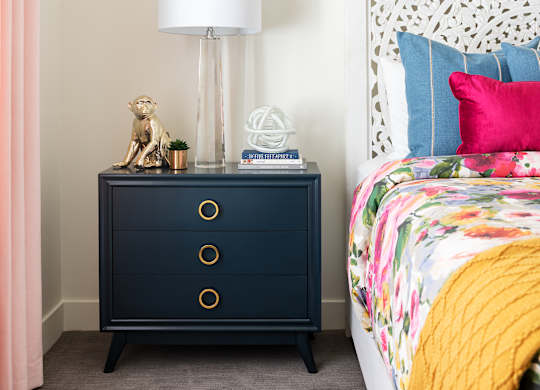 A bedroom with a bed, a nightstand with a lamp, and a curtain.