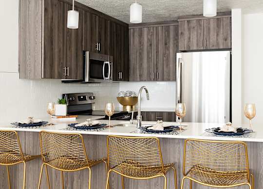 A modern kitchen with a bar area and chairs.