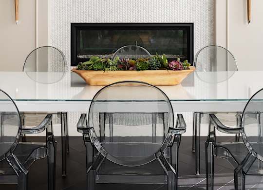 A modern dining room with a glass table and black chairs.