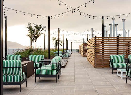 A patio with green striped chairs and wooden tables.