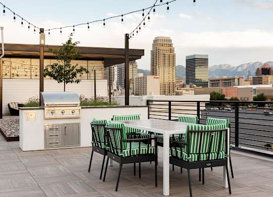A patio with a table and chairs overlooking a city skyline.