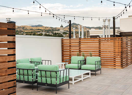 A patio with green striped chairs and a view of the city.
