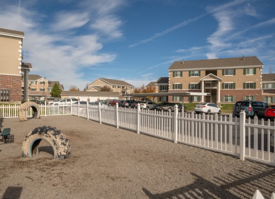 a fenced in dog park in front of a building