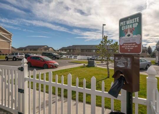 a white picket fence with a sign that says pet waste clean up