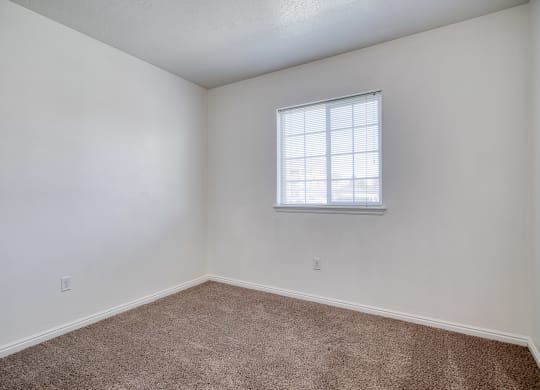 a bedroom with white walls and a window