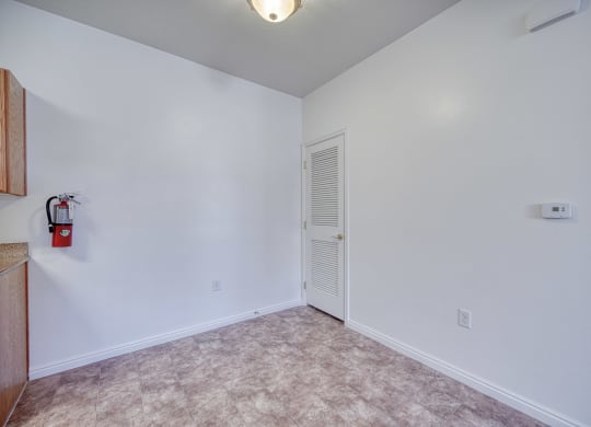 a bedroom with white walls and a white door with a fire extinguisher on the wall