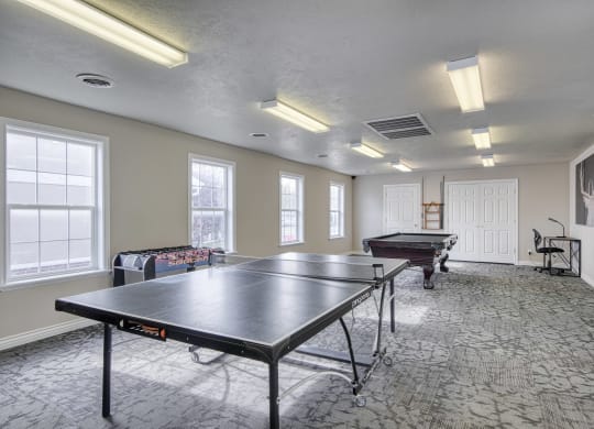 a recreation room with two ping pong tables and a foosball table