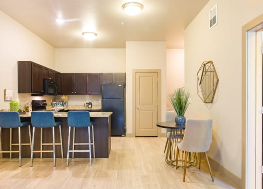 a kitchen with a bar and stools next to a living room with a refrigerator at Sugar House Apartments By Urbana, Salt Lake City, UT, 84105