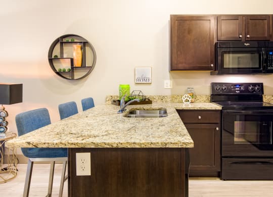 a kitchen with a granite counter top and black appliances at Sugar House Apartments By Urbana, Salt Lake City, UT, 84105