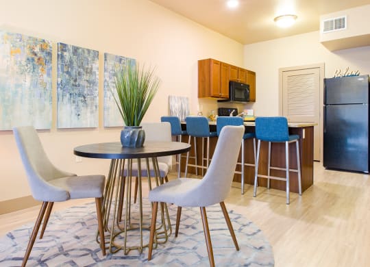 a dining room with a table and chairs and a kitchen with a refrigerator at Sugar House Apartments By Urbana, Salt Lake City, UT, 84105