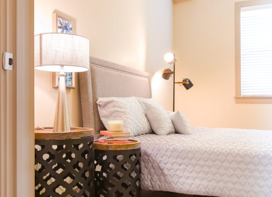 a bedroom with a bed and a nightstand with a lamp at Sugar House Apartments By Urbana, Salt Lake City, UT, 84105