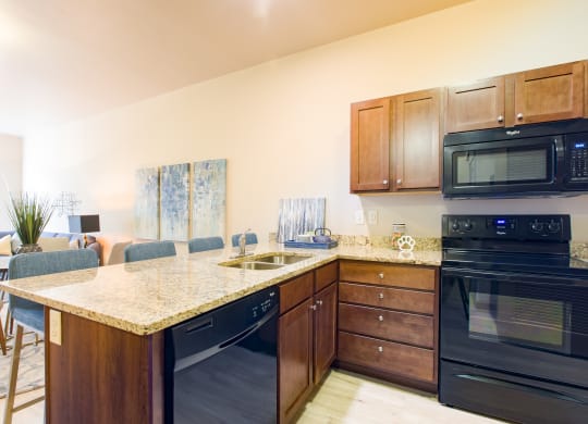 a kitchen with black appliances and a granite counter top at Sugar House Apartments By Urbana, Salt Lake City, UT, 84105