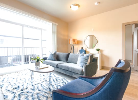 a living room with a large window and blue chairs at Sugar House Apartments By Urbana, Salt Lake City, UT, 84105