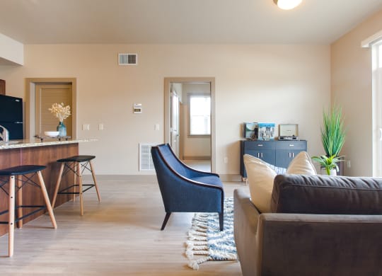 a living room with a couch chair and a kitchenette in the background at Sugar House Apartments By Urbana, Salt Lake City, UT, 84105