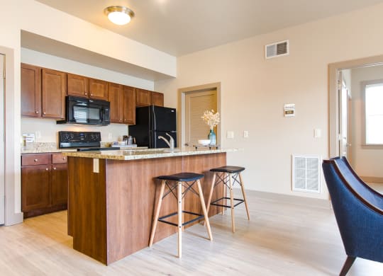 a kitchen with an island and stools at Sugar House Apartments By Urbana, Salt Lake City, UT, 84105