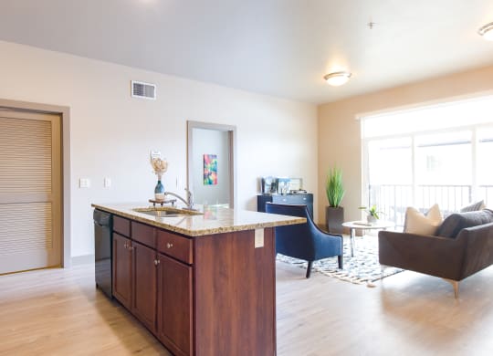 a kitchen with an island and a living room in the background at Sugar House Apartments By Urbana, Salt Lake City, UT, 84105