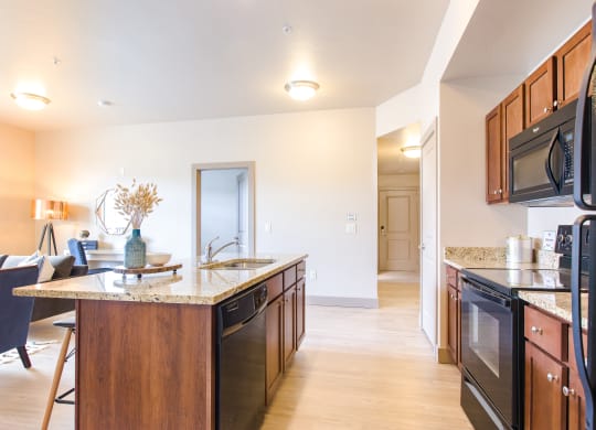 a kitchen with an island and a living room in the background at Sugar House Apartments By Urbana, Salt Lake City, UT, 84105