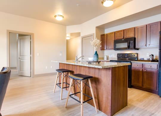 a kitchen with an island and stools at Sugar House Apartments By Urbana, Salt Lake City, UT, 84105