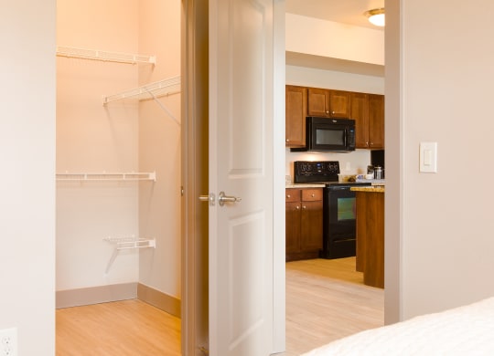 a bedroom with an open door and a kitchen in the background at Sugar House Apartments By Urbana, Salt Lake City, UT, 84105