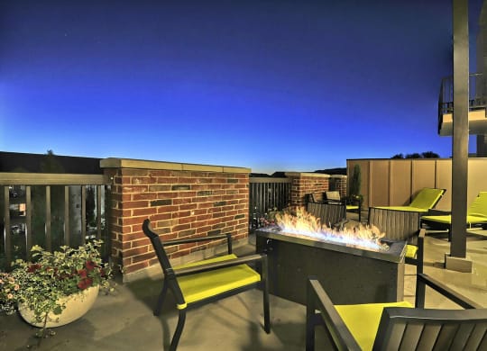 a fire pit and lounge area on the patio of an apartment building at night