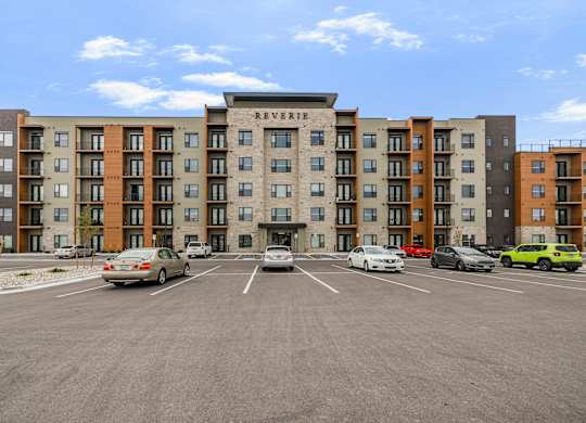A parking lot in front of a multi-story apartment building named Reverie.
