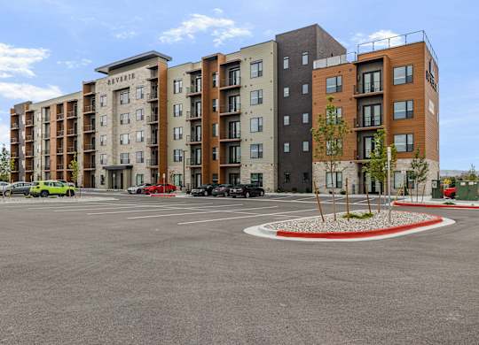 A parking lot in front of a multi-story apartment building.
