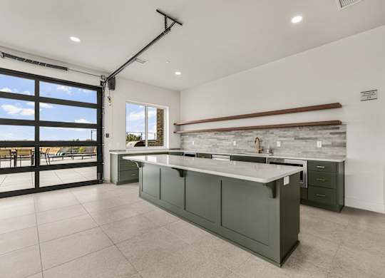 A modern kitchen with a large island and a view of the outdoors.