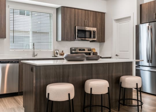 a kitchen with a large island with three stools in front of it