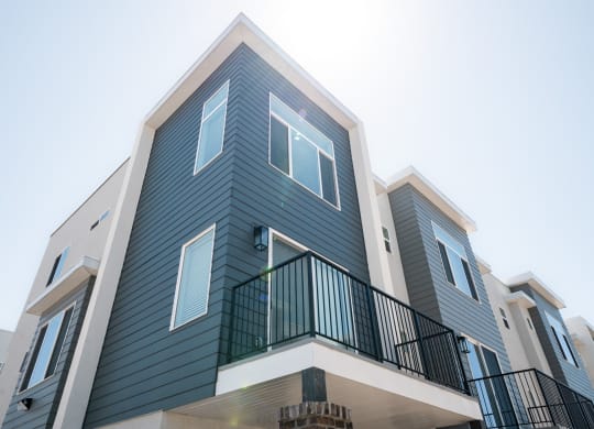 a row of apartments with blue siding and a blue sky in the background