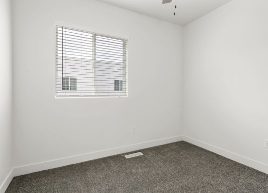 a bedroom with white walls and a window