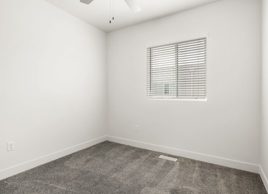 a bedroom with white walls and a window