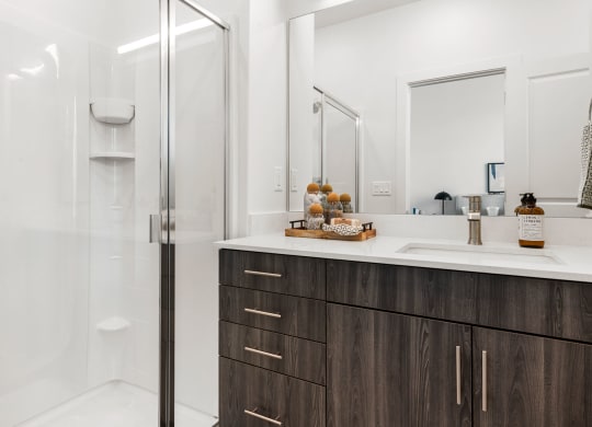 a bathroom with white walls and a wooden vanity with a white countertop