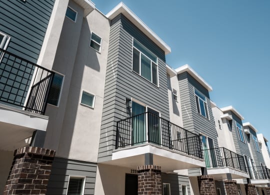 a row of apartment buildings with grey siding and blue windows