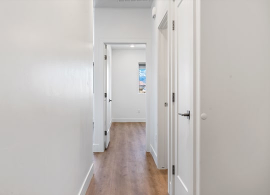 an empty hallway with white walls and wood floors