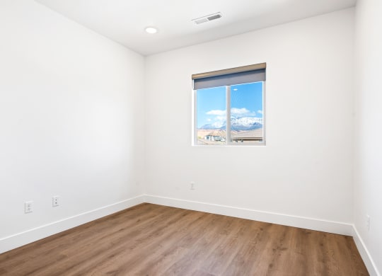 a room with white walls and wood floors and a window