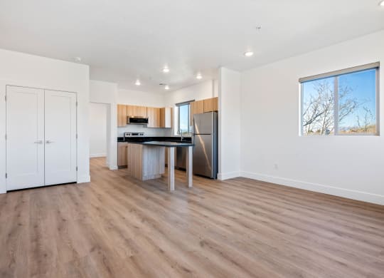 an empty living room with a kitchen with a large window
