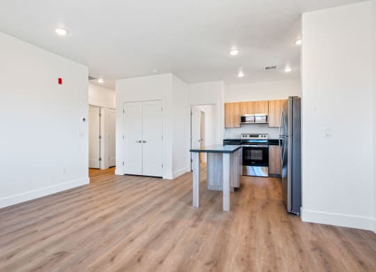 a renovated living room and kitchen with wood flooring and white walls
