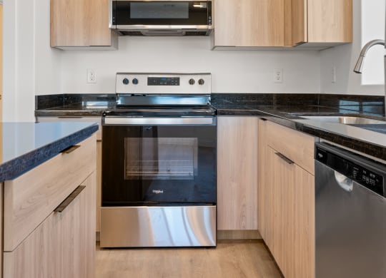 a kitchen with wooden cabinets and black counter tops and stainless steel appliances