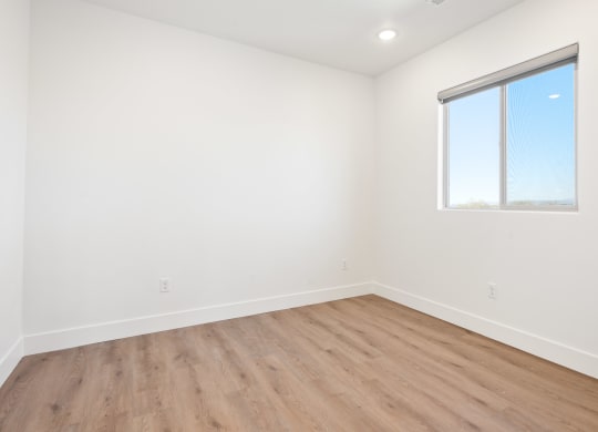 an empty room with wood floors and a window