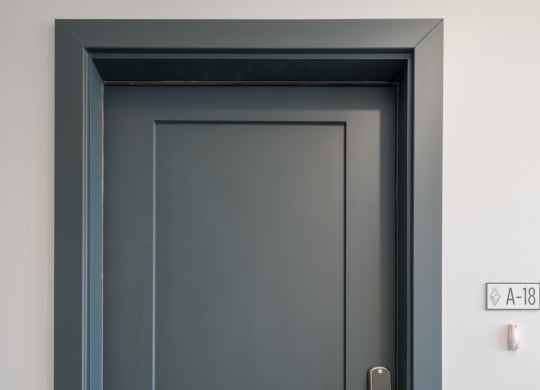 a black door with a silver door handle and a white wall