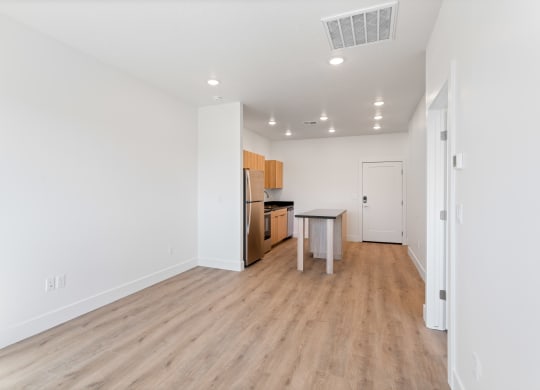 a living room and kitchen with white walls and wood flooring