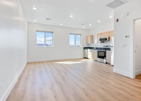 an empty living room and kitchen with wood floors and white walls