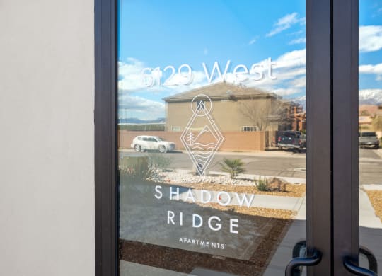a window with a reflection of a building with a shadow ride sign on it