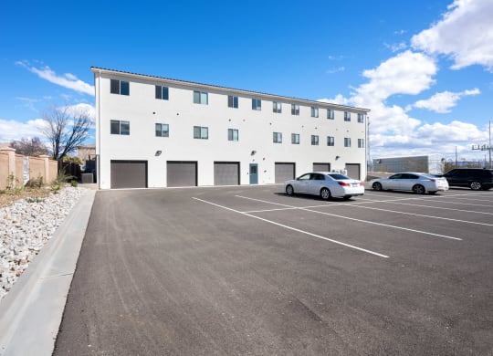 an empty parking lot with cars in front of a white building