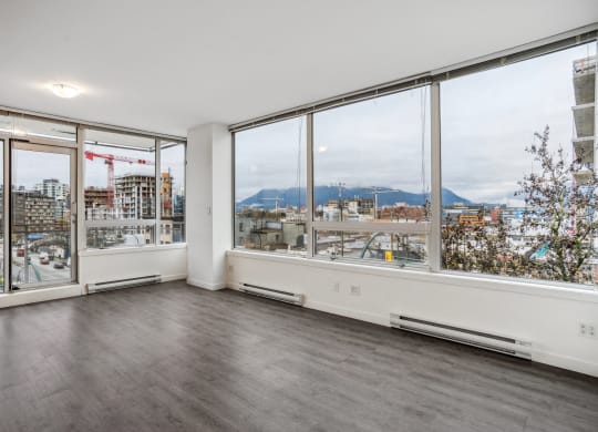 an empty living room with large windows and a city view