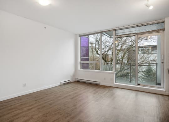 an empty living room with a large window and wood floors