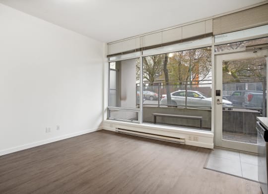 an empty living room with a large window and wood flooring