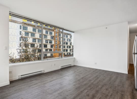 an empty living room with a large window and white walls