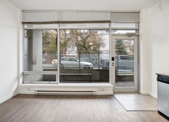 an empty living room with a large window and a car outside